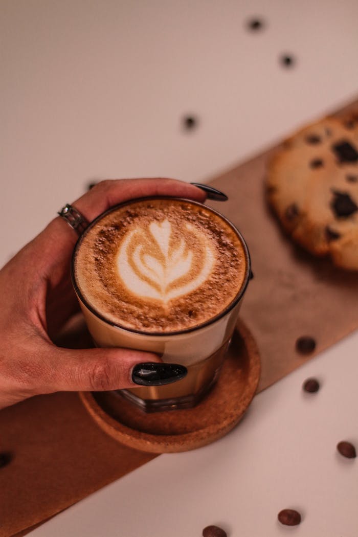 about-01 A cup of latte with art and a chocolate chip cookie, perfect for coffee enthusiasts.