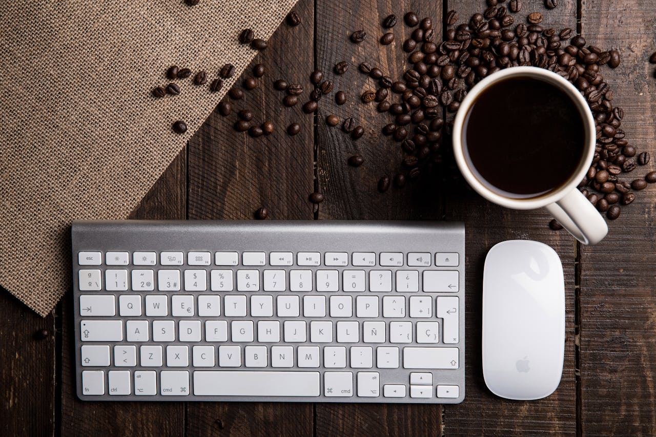 Top view of a coffee cup with keyboard and mouse on a rustic wooden desk.