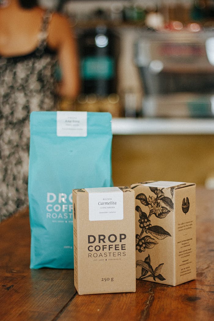 why-choose-us High-quality coffee packaging displayed on a wooden tabletop in a cozy café environment.